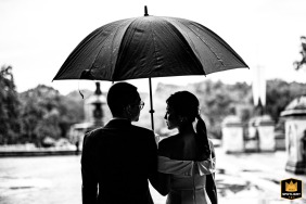 In Central Park, the couple is photographed from behind in a black and white image, standing close together beneath a single umbrella, their quiet intimacy beneath the rainy sky evoking a deeply personal promise.